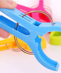 Close-up of blue clip from Heavy Duty Beach Towel Clips For Chairs And Loungers, Windproof Clips To Keep Towels, Swimsuits, And Gear From Blowing Away On Beach, Pool, Or Cruise Deck
