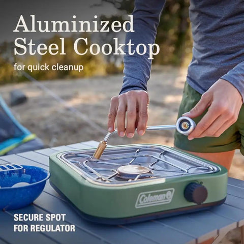 Person handling Cascade 18 1-Burner Camping Stove With 8000 BTU Output And Matchless Lighting, outdoor setup, green aluminized steel cooktop