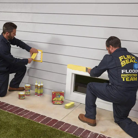 Two men applying Flood Protection Tape 3.75 Inch By 50 Foot Waterproof Rubberized Tape Removable Seal on a window casing.