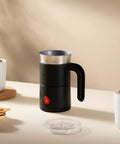 Tabletop view of Electric Milk Frother With Handle That Delivers Barista Quality Foam From 3 To 10 Ounces In A Stainless Steel Nonstick Cup