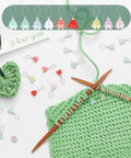 Flower Stitch Markers Set Of 18 In 9 Colors For Knitting Crochet And Weaving With Acrylic Markers And Stainless Steel Wire shown on green yarn