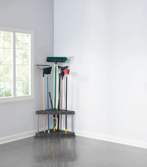 Corner Garage Tool Tower Rack That Holds 30 Long Handled Tools Rakes Brooms Shovels Easy to Assemble Space Saving Wall Mount Storage for Home Shed Shop Backyard in corner of a room with tools.