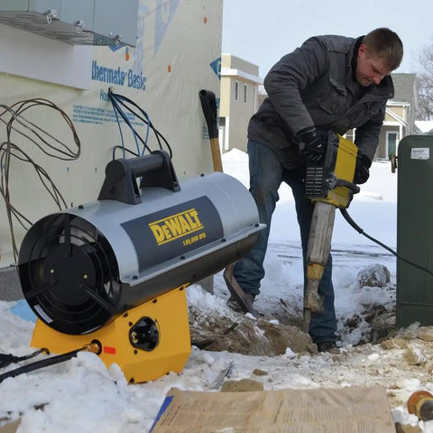 Rock Solid 150000 BTU Propane Forced Air Job Site Heater in use on snowy worksite with worker operating tool nearby.