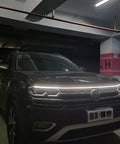 Car with a 70 Inch White LED DRL Car Hood Light Strip With Dynamic Scan Start Up For Cars Trucks And SUVs 12V Flexible Waterproof Exterior Light Bar for enhanced night visibility.