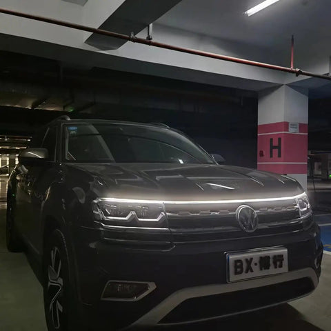 Car with a 70 Inch White LED DRL Car Hood Light Strip With Dynamic Scan Start Up For Cars Trucks And SUVs 12V Flexible Waterproof Exterior Light Bar for enhanced night visibility.