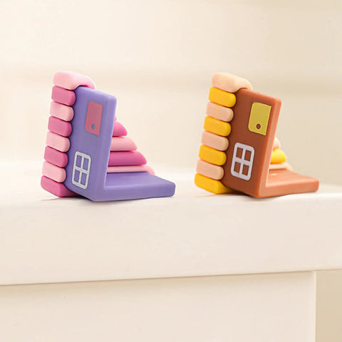 Colorful rubber door stops shaped like houses on a white surface