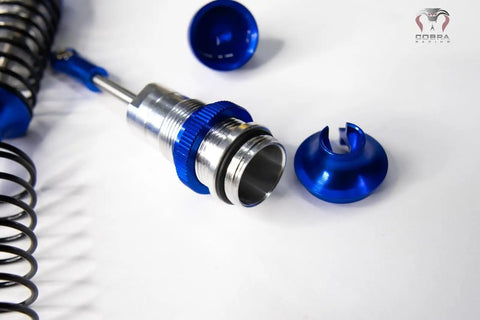 Close-up of Blue Aluminum BigBore Shocks for 4x4 and 2WD Trucks, showing disassembled parts and spring detail.