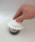 Universal Bathroom Hair Catcher Strainer With Suction Cup For Tub Drains being placed by hand over a drain