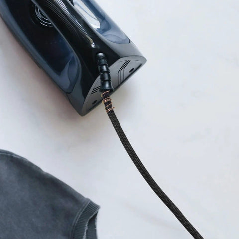 Close-up of flexible and leak-resistant heavy duty high temperature steam hose for steam irons with durable tubing attached to iron.