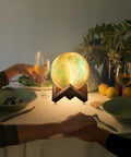 Galaxy Lamp With Wooden Stand 16 LED Color Changing Night Light on dining table, creating ambient lighting with wine glasses.