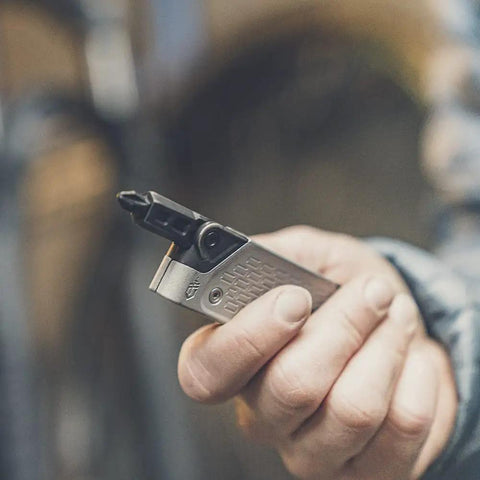 Close-up of hand holding Lockdown Driver 7 In 1 EDC Multitool with 2.5 inch plain edge blade and bit driver, survival gear.