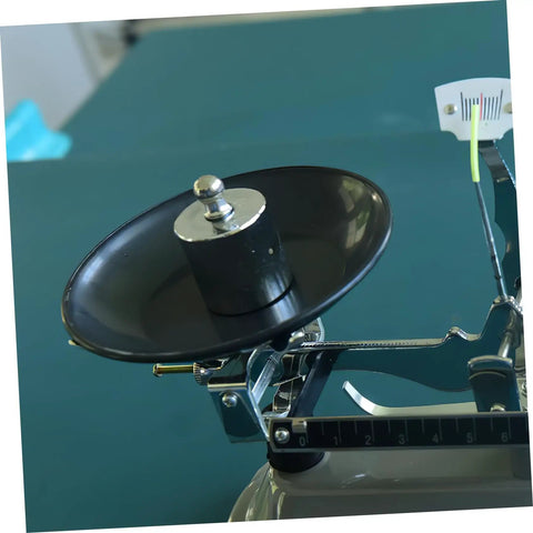 High Precision Calibration Weights For Digital Scales And Lab Use on a mechanical balance with black weighing pan
