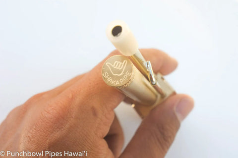 Hand holding Durable Brass Portable Tar Trap With Longer Stem And Mega Storage Pod Easy Open Closeable Lid Made In Hawaii