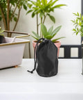 Black waterproof rain gear storage bag with drawstring on a table, part of Two Pack Waterproof Rain Gear Storage Bags With Drawstring Pouches