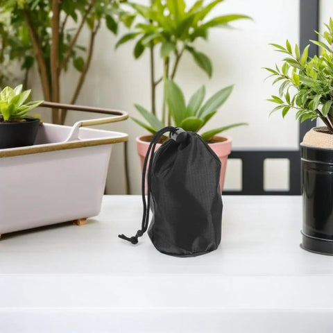 Black waterproof rain gear storage bag with drawstring on a table, part of Two Pack Waterproof Rain Gear Storage Bags With Drawstring Pouches