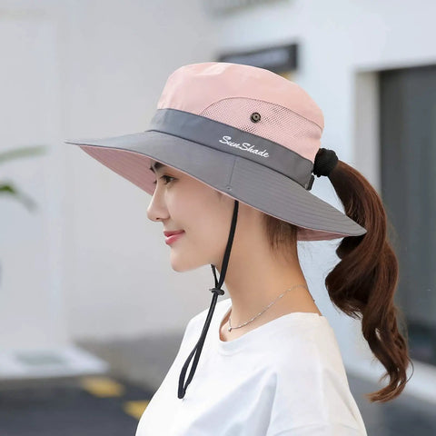 Woman wearing Women's Ponytail Safari Sun Hat With Wide Brim And UV 50 Protection, side view, showing chin drawstring.