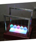 Red glowing pendulum desk decor Newton's cradle ornament for home office demonstrates physics energy conservation battery operated fun requires 4 AA batteries not included