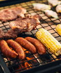 Adjustable Swivel Grill Grate For Open Fire Cooking With Spike Pole Steel Mesh Wire Grate loaded with sausages and corn on the cob