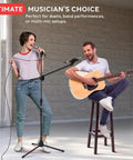 Pair Of Universal Adjustable Tripod Microphone Stands Heavy Duty Lightweight Stage Studio Boom Mic Holders With Carry Bag Five Eighths Inch Adapter Kit in use by performers singing and playing guitar.