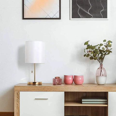 Lit Gold Nightstand Lamp With Metal Base And Fabric Shade on wooden desk in modern room setting