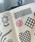 Close-up of Upgraded 2026 Embroidery Stitch Book Kit With 86 Piece Starter Set showing stitch patterns on fabric.