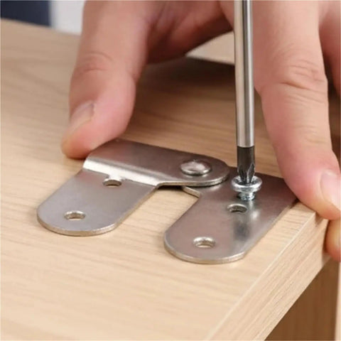 Person assembling Built Tough Ladder Folding Hinge Heavy Duty Invisible Tabletop Bracket with a screwdriver on wood surface.