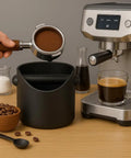Compact Coffee Knock Box 4.6 Inch Barista Style Espresso Grounds Holder with Removable Plastic Knock Rod next to espresso machine.