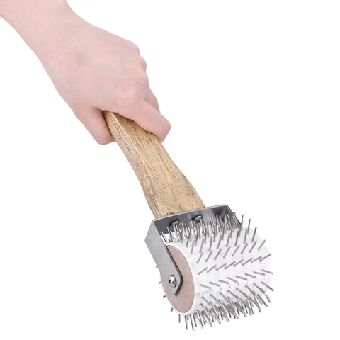 Hand holding Honey Uncapping Roller Manual Honey Extractor with plastic needle roller and wooden handle.