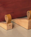 Pair of Walnut Wood Door Stopper Wedge With PU Finish on floor against a brown door, showcasing Nordic style and easy assembly.