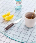 Premium Tempered Glass Lazy Susan Turntable Featuring A Sleek Swivel Design with coffee, knife, and lemon on a dining table.