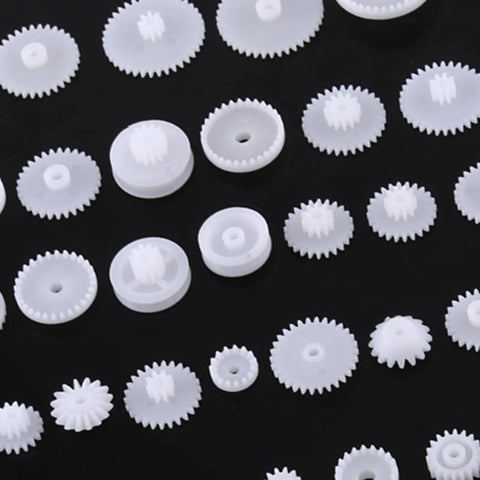 Grab This Awesome DIY Robot Gears And Pulley Belt Kit With 64 Kinds Of Wearable Plastic Parts Perfect For Tech Models, Car Robots, And Cool Motor Projects You Can Build Your Own Stuff With Today. white plastic gears on black background