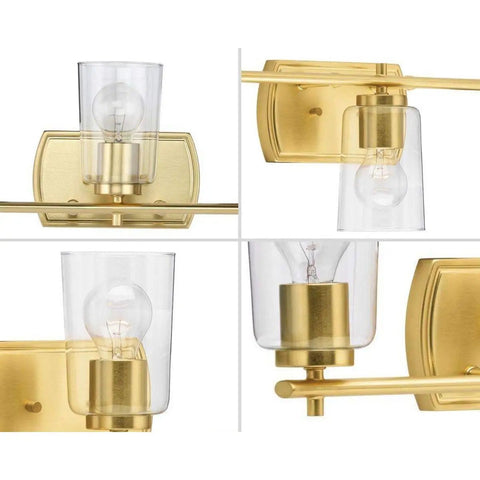 Adley Collection 3 Light Clear Glass Bath Vanity Light in Satin Brass, sleek brass backplate and clear glass shade close-up.
