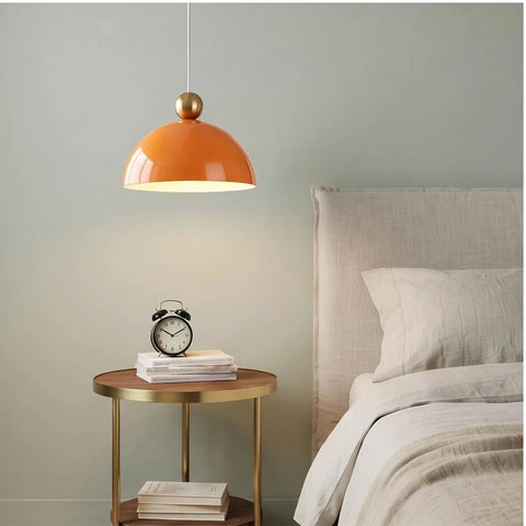 MIELPOXS Modern Dome Pendant Light Iron Metal Hanging Ceiling Fixture in orange above a bedside table with clock.