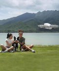 4K Camera Drone Bundle With Intelligent Flight Battery And Carrying Bag capturing a scenic aerial shot by a lakeside with people and a dog.