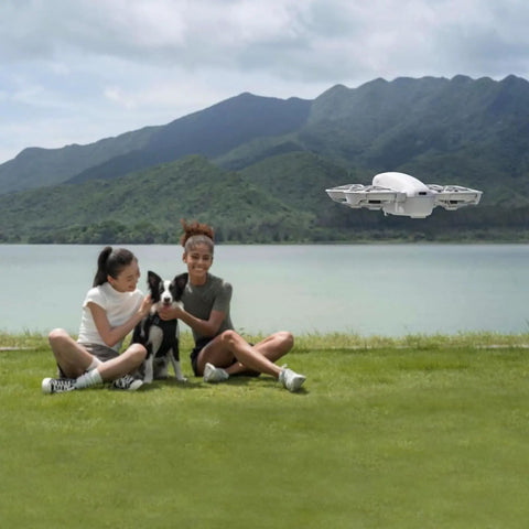 4K Camera Drone Bundle With Intelligent Flight Battery And Carrying Bag capturing a scenic aerial shot by a lakeside with people and a dog.