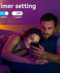Couple relaxing with Two Rolls Of Hundred Feet LED Strip Lights 24V 5050 RGB Color Changing With App Control Music Sync Remote Non Waterproof For Bedroom Gaming Setup And Home Decor in background.