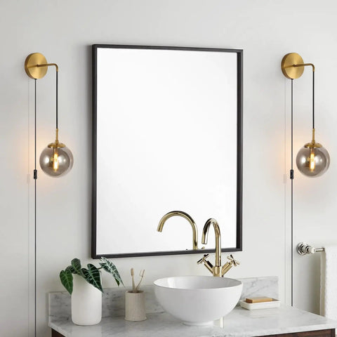 Set Of 2 Plug-In Wall Sconces With Brushed Brass Finish And Smoke Grey Glass Globes beside bathroom mirror