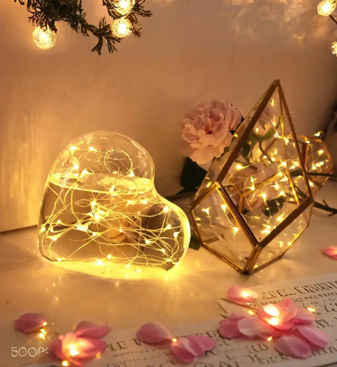 Six Pack Battery Operated Fairy Lights With Timer And Remote Six Point Five Foot Copper Wire 20LED Warm White Twinkle Lights Waterproof Firefly String shown in heart and geometric glass decor.