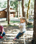 Child riding a Heavy Duty Wooden Zip Line Seat for Backyard Adventures, Pine Wood Frame Holds Up To 350 Lbs, Soft White Rope.