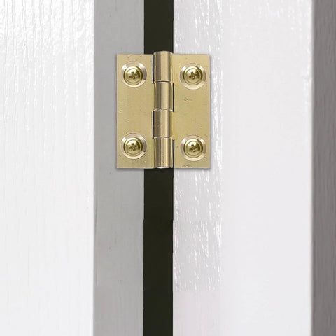 Close-up of brass foldable cabinet door hinge with screws on white door.