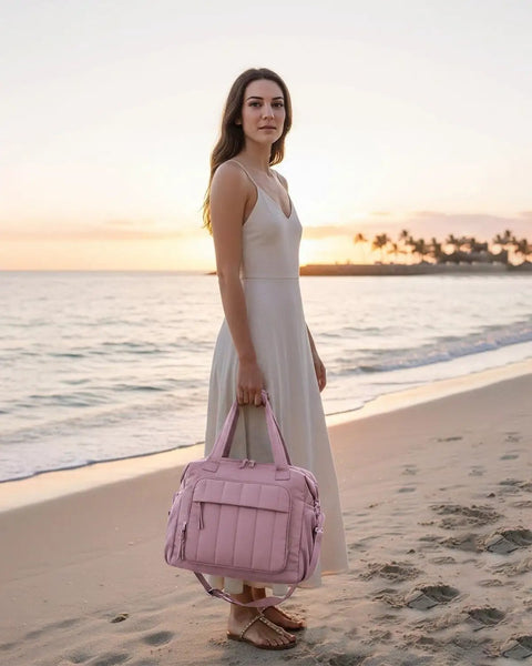 Woman on beach at sunset holding a pink insulated soft travel duffel bag. Crush The Summer Heat With This Snazzy Puffer Cooler Bag Stowing 35 Frosty Drinks Inside An Insulated Soft Travel Duffel Crafted For Pink Tailgates And Beach Days.