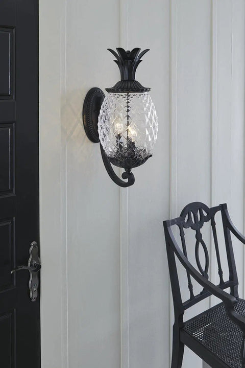 Three Light Outdoor Wall Mount Sconce In Matte Black With Pineapple Cut Glass, porch view with decorative chair.
