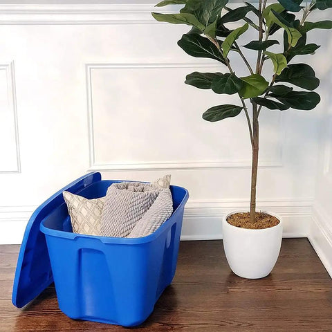 Open 4 Pack 18 Gallon Blue Plastic Storage Bin With Lid next to plant, showing pillows inside for bedroom, kitchen, and garage organization