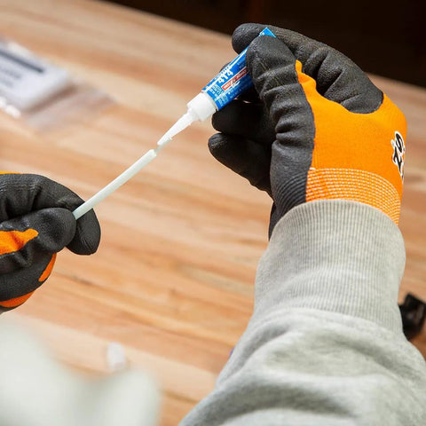 Klein Tools 56025 non-conductive fish tape repair kit, close-up view of gloved hands applying adhesive to fish tape.