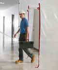 Worker using Heavy Duty Dust Barrier Zipper 2 Pack Self Adhesive Entry Door For Remodeling Jobs Red HDAZ2 in construction area.
