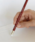 Hand using Mitsubishi Pencil With Eraser 9850 HB Hardness For School Or Office on notebook paper, smooth lead, red finish.