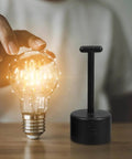 Nonslip Socket Ring Removal Tool For E14 E26 E27 G9 Lamps No Sweat Install tool next to glowing light bulb on wooden surface