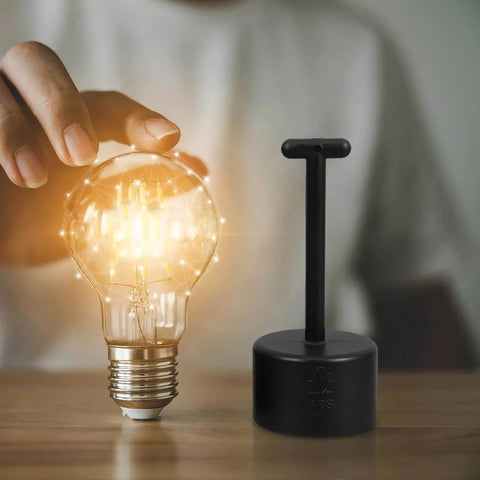 Nonslip Socket Ring Removal Tool For E14 E26 E27 G9 Lamps No Sweat Install tool next to glowing light bulb on wooden surface