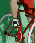 Cyclist using 2 Pack Toe Clip Pedals With Straps For Road And Commuter Bikes, adjustable foot cages, and durable nylon straps on red bicycle.