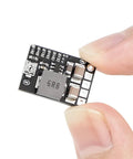 Close-up of a black mini DC buck converter board held by fingers, part of the Five Pack Mini DC Buck Converter Set 4.5 to 20V Input to 5V Output.